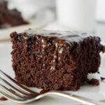 slice of chocolate depression cake, with glass of milk in background.