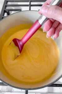 stirring cheese soufflé batter on stovetop