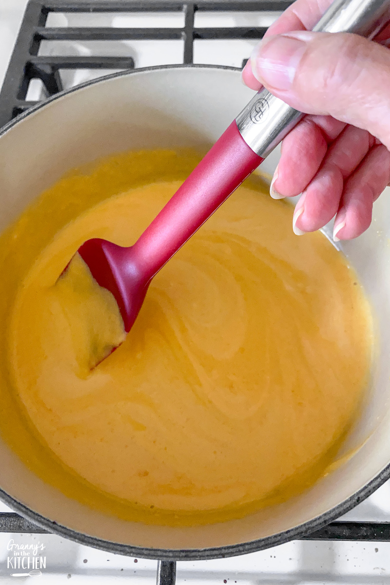 stirring cheese soufflé batter on stovetop