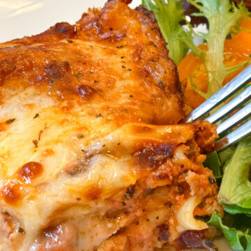 slice of homemade lasagna with salad