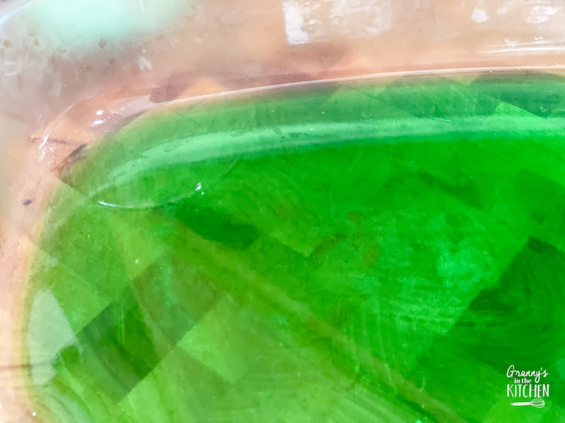 green jello in the bottom of a glass dessert dish