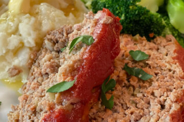 sliced meatloaf on plate with potatoes and broccoli