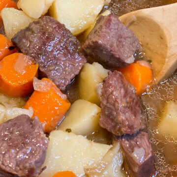 beef stew in pot with wooden spoon