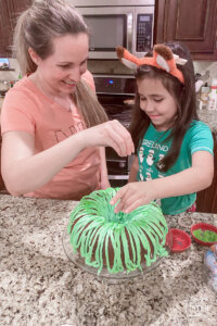mom and daughter putting sprinkles on a green bundt cake