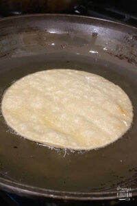 frying a corn tortilla in pan