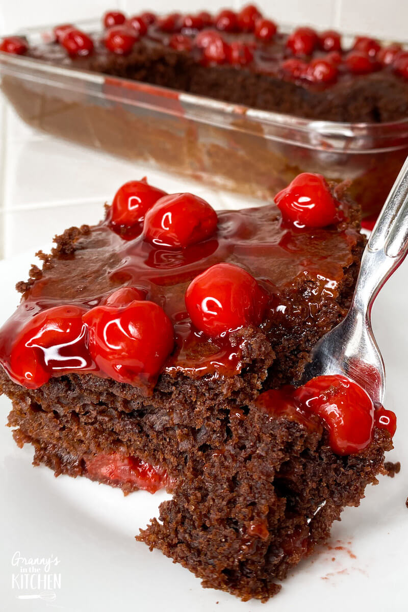 fork cutting into a slice of cherry chocolate cake
