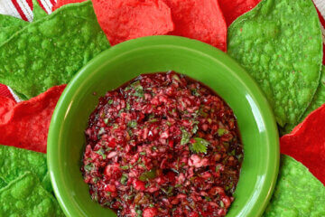 bowl of cranberry salsa surrounded by red and green tortilla chips