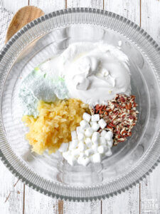 glass mixing bowl with cool whip, fruits, and nuts