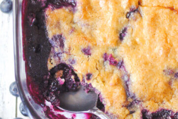 close up of a corner of a dish of homemade blueberry cobbler; text overlay "The Best Blueberry Cobbler"
