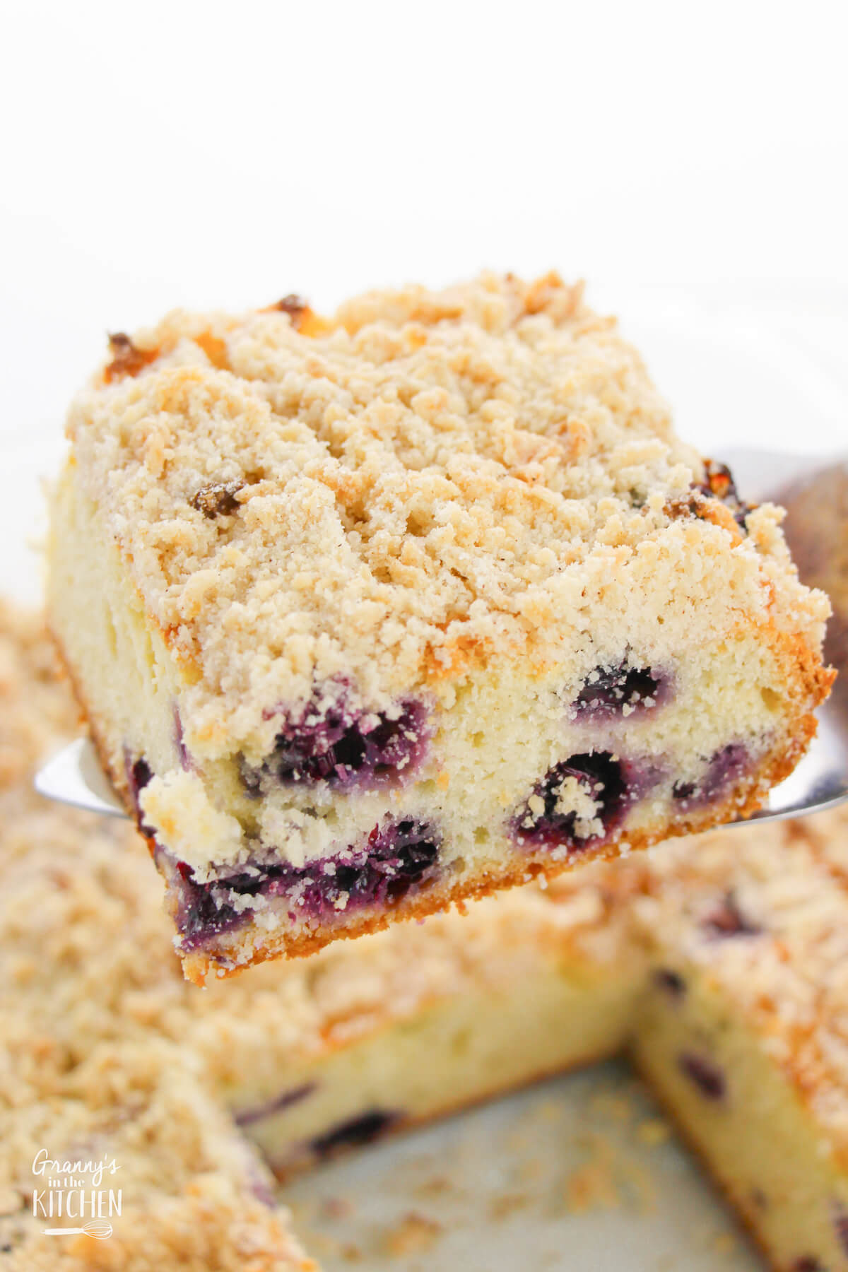pulling a slice of blueberry coffee cake out of the pan