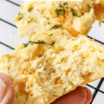 holding a biscuit with bite taken to show detail; text overlay "Cheddar Bay Biscuits"