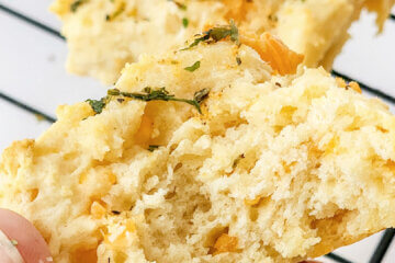 holding a biscuit with bite taken to show detail; text overlay "Cheddar Bay Biscuits"