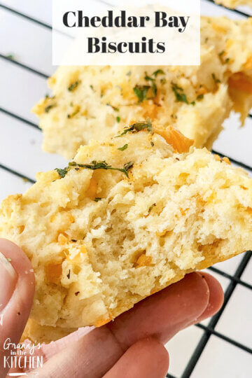 holding a biscuit with bite taken to show detail; text overlay "Cheddar Bay Biscuits"