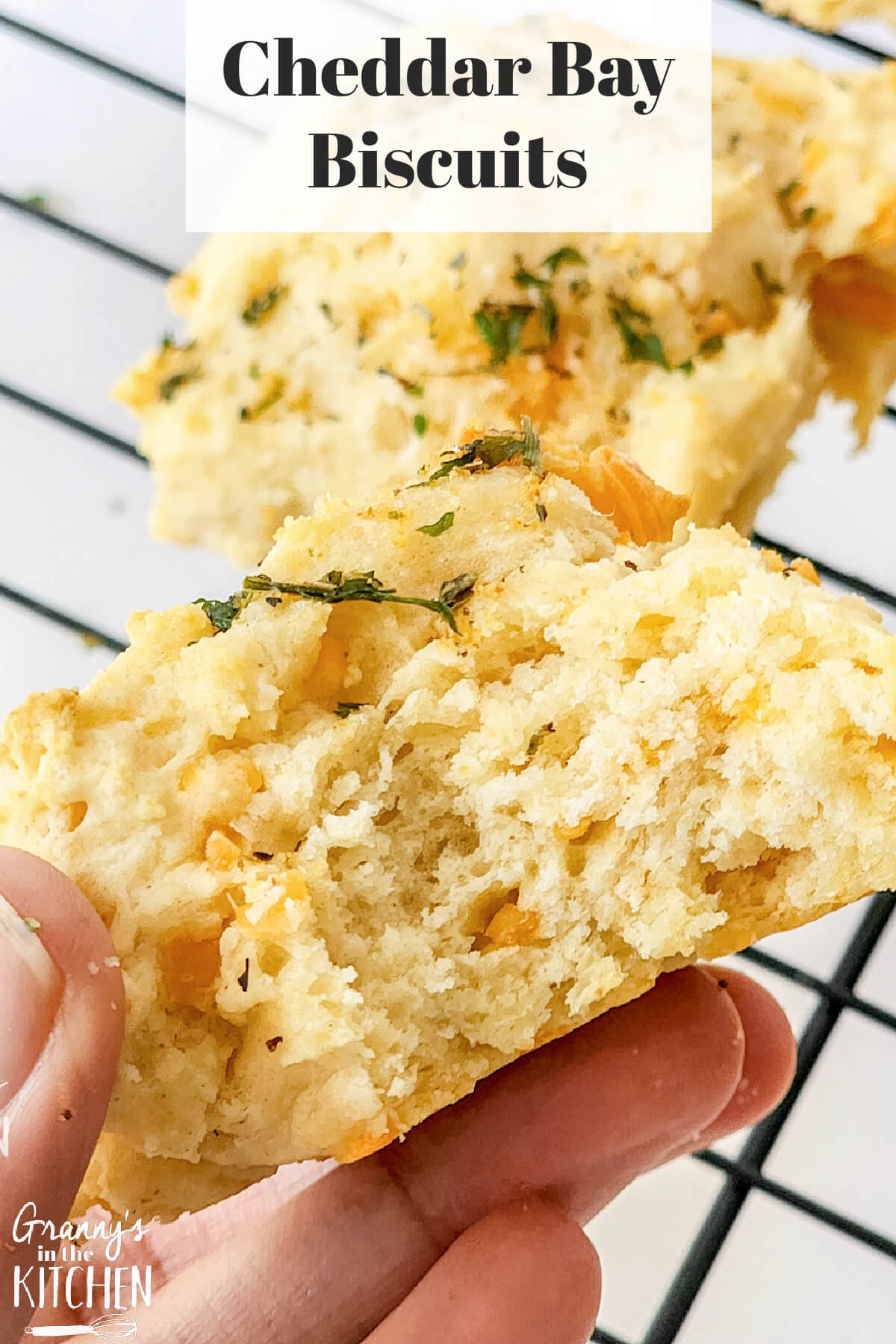 holding a biscuit with bite taken to show detail; text overlay "Cheddar Bay Biscuits"