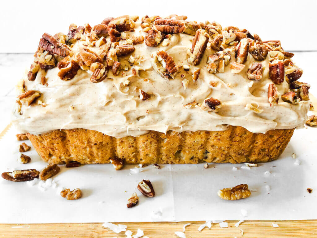 loaf of banana bread with cream cheese icing and pecans