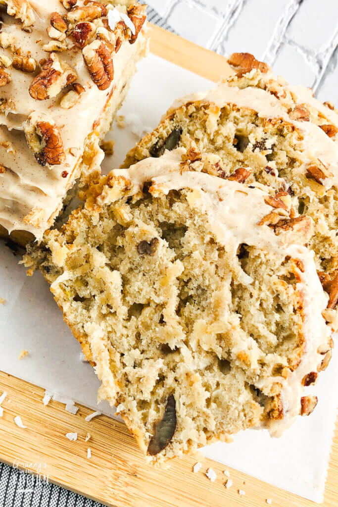 sliced hummingbird bread with frosting and pecans on top