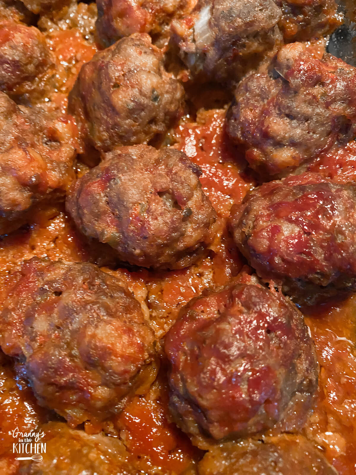 close up of meatballs cooking in barbecue sauce