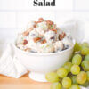 bowl of grape salad on wooden countertop with fresh grapes; text overlay "Creamy Grape Salad"