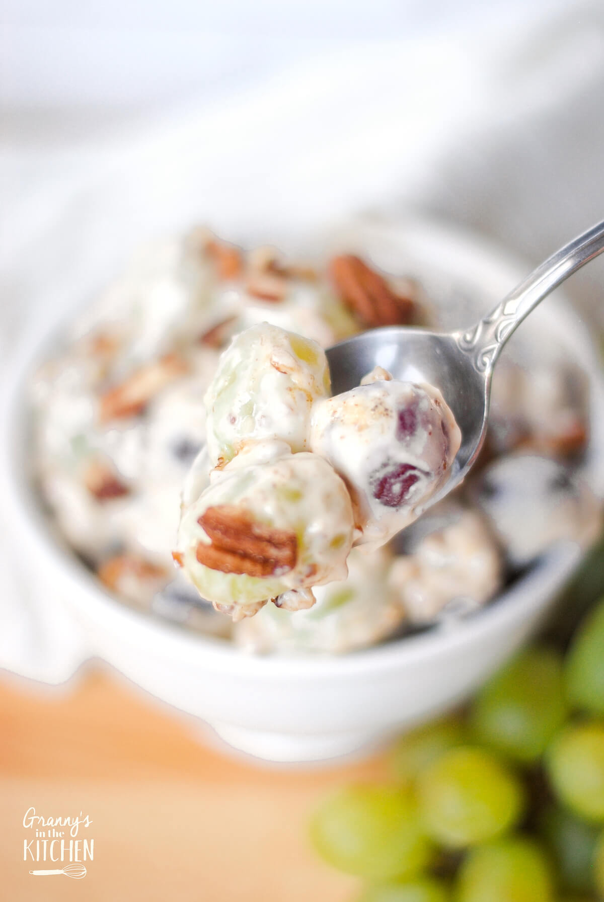 spoon with three grapes in a creamy dressing
