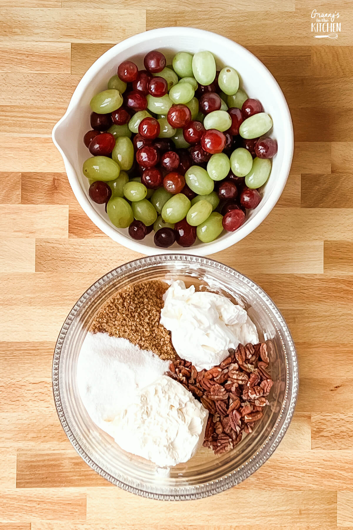 bowl of red and green grapes and a bowl of ingredients to make creamy fruit salad dressing