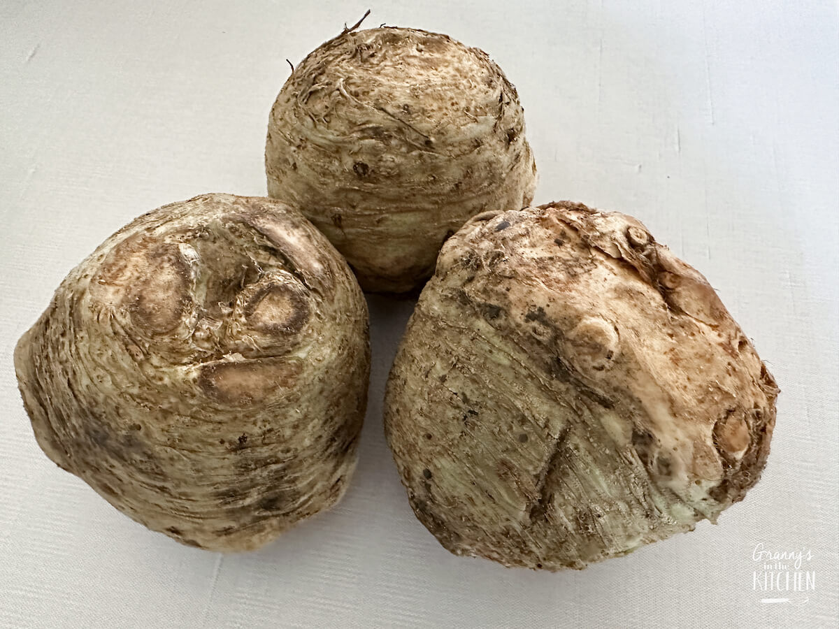 3 whole celery roots on white background