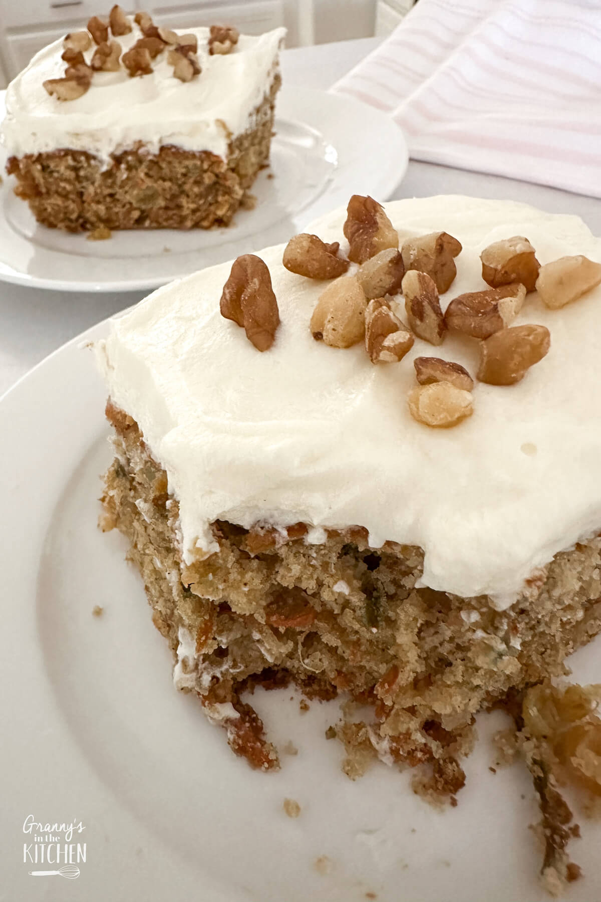 top down view of two plated pieces of carrot cake, one with a bite missing