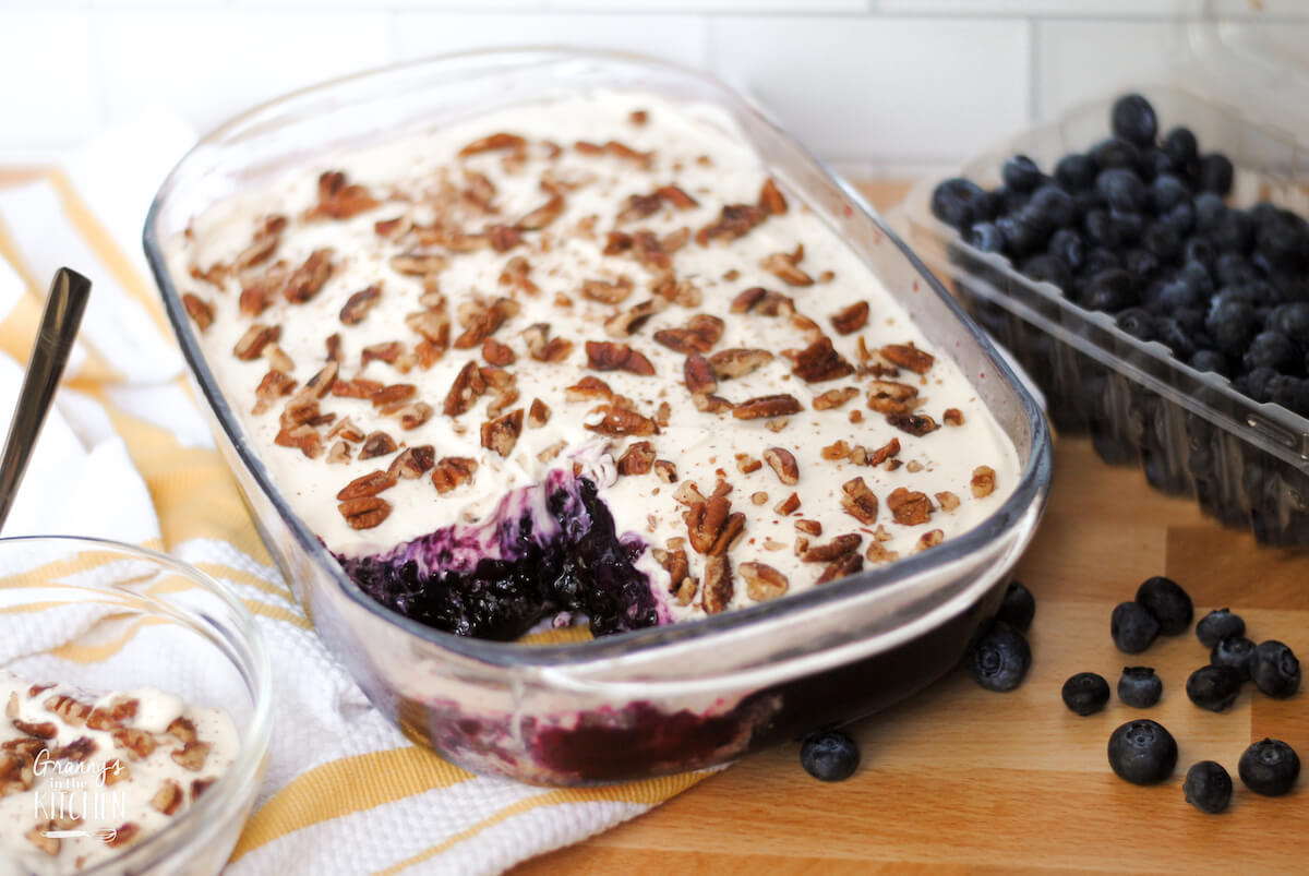 layered blueberry jello salad in a baking dish, topped with pecans; box of fresh blueberries