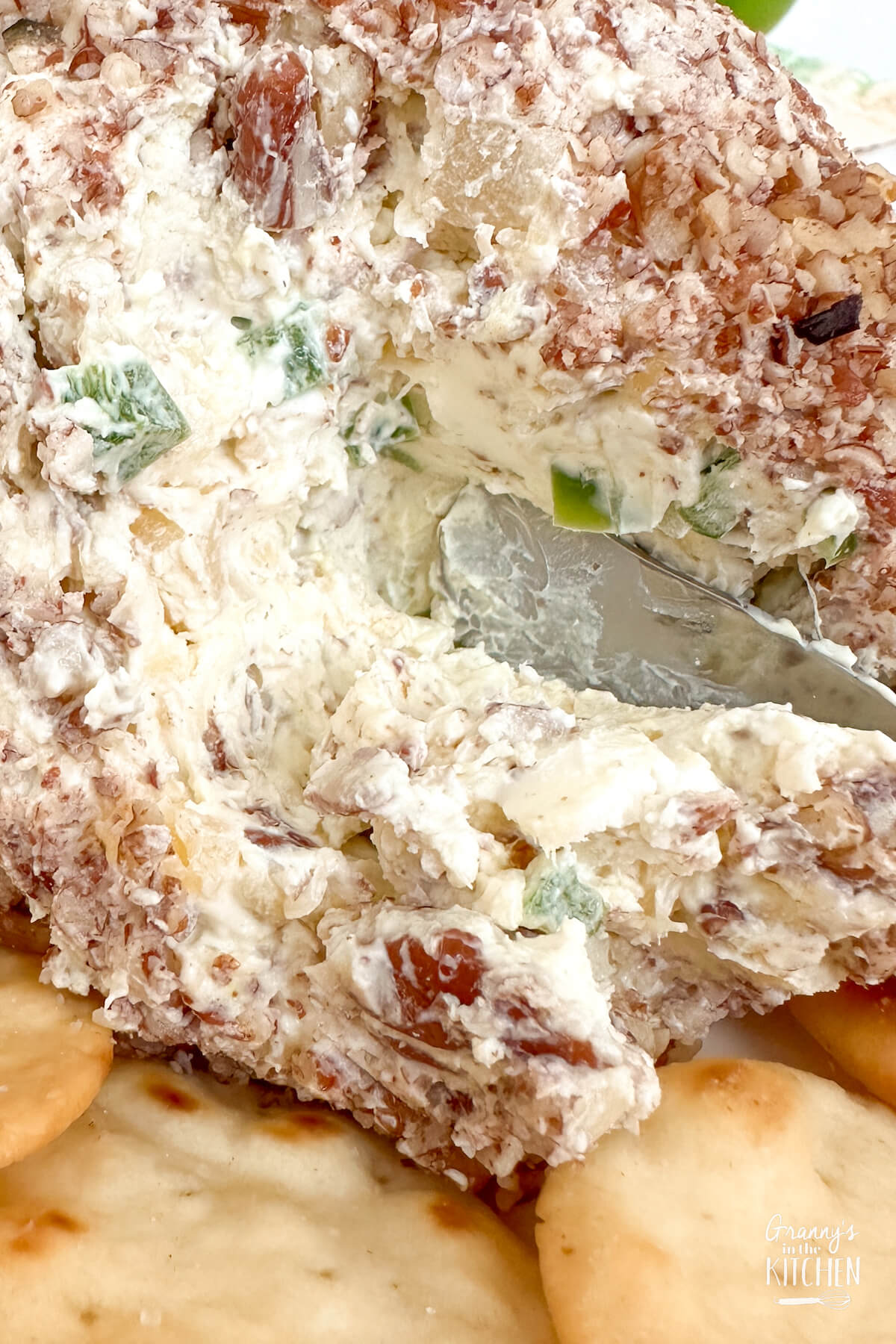 close up of a butter knife cutting into a homemade cheese ball appetizer