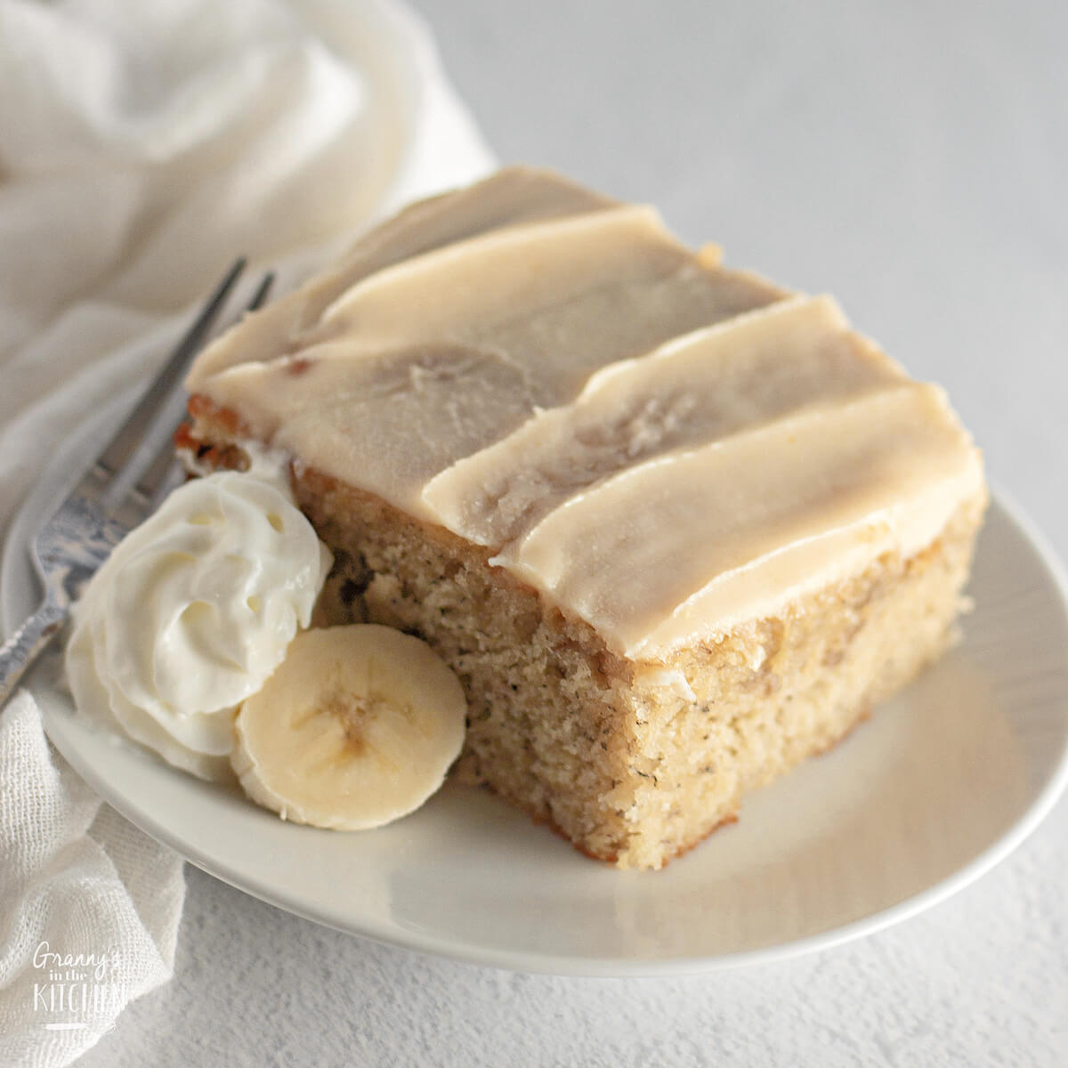 plate of iced banana coffee cake with whipped cream