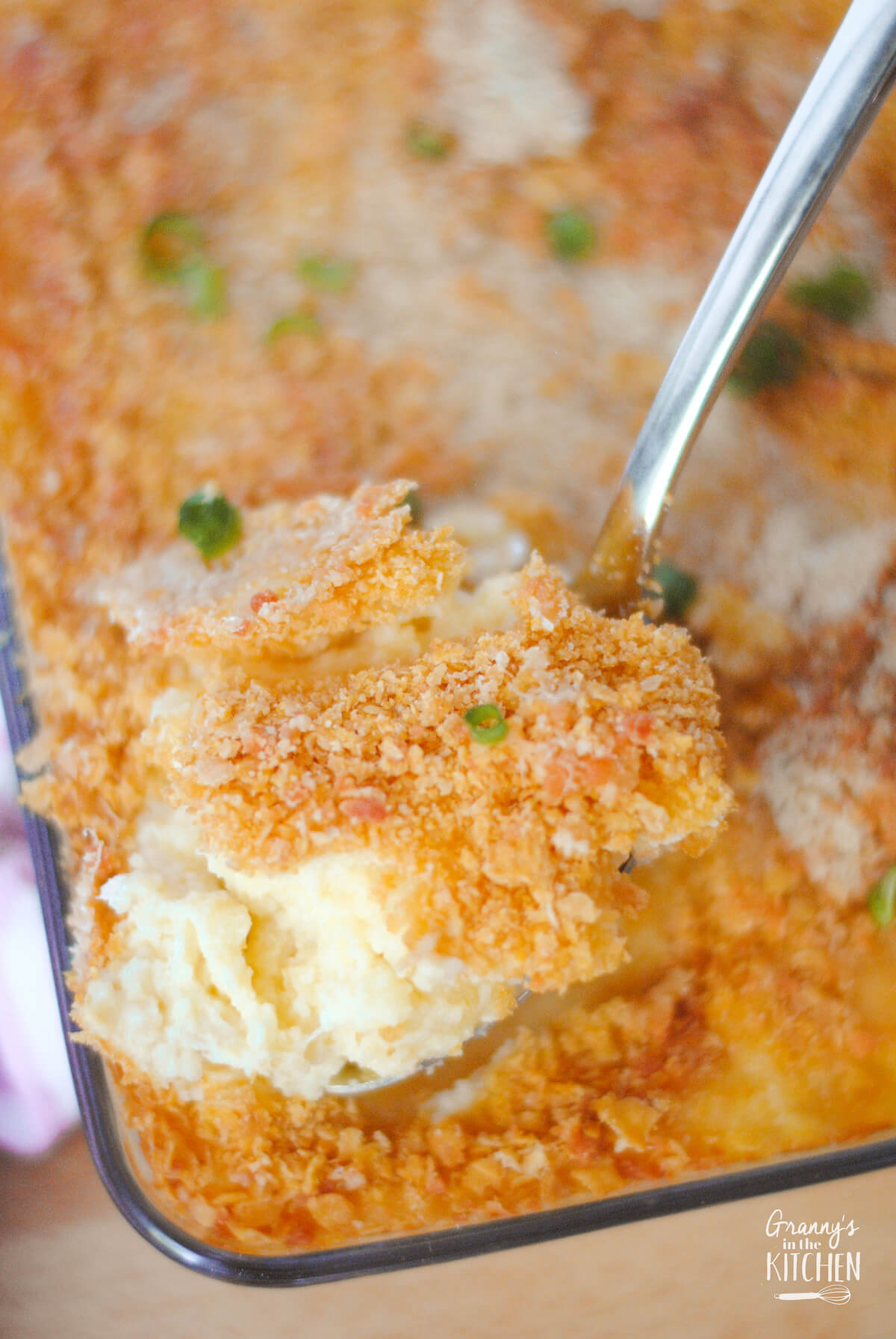 scooping a serving of baked mashed potatoes with a crispy topping.