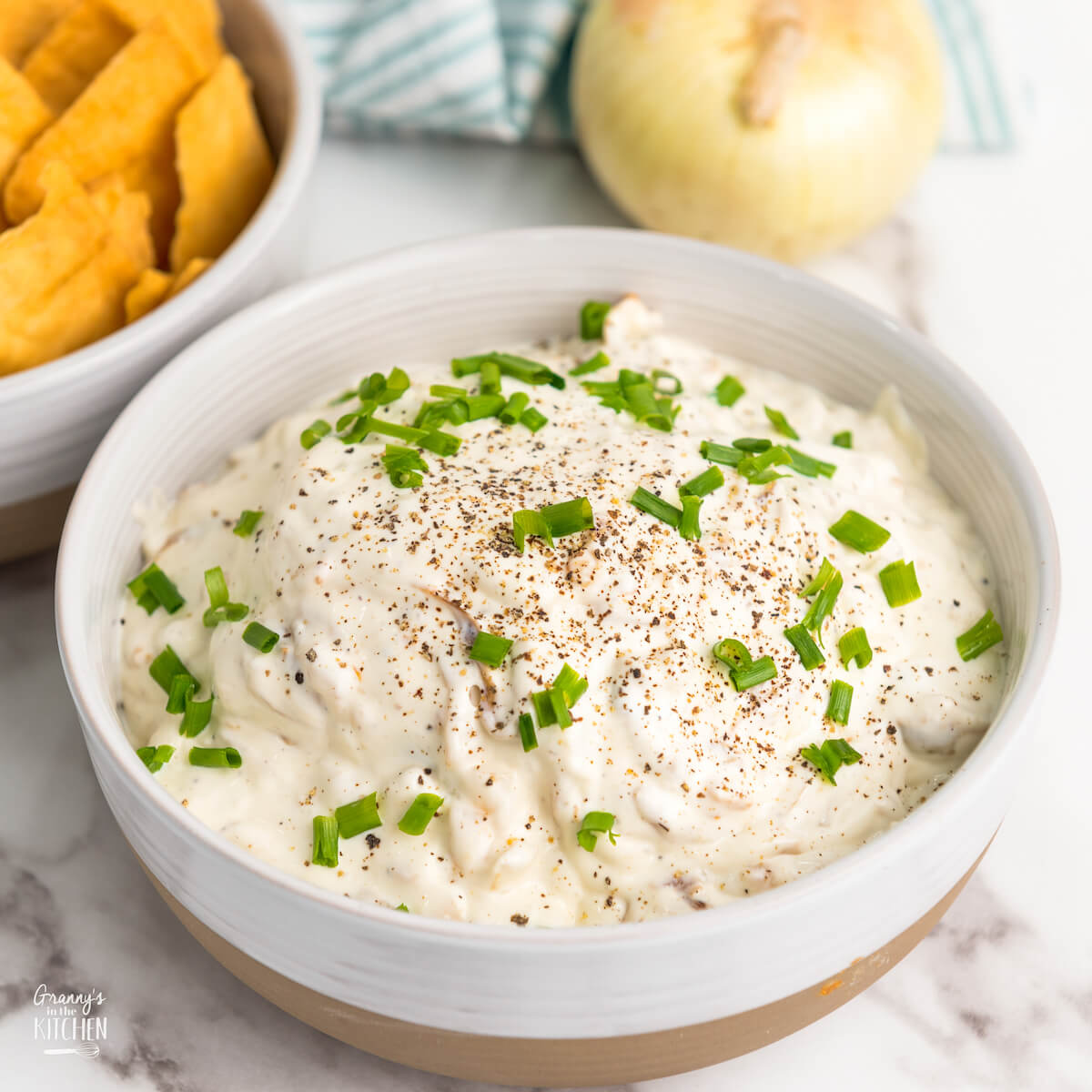 bowl of homemade French onion dip, next to a bowl of pita chips.