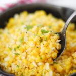 scooping up corn with a spoon, from a skillet