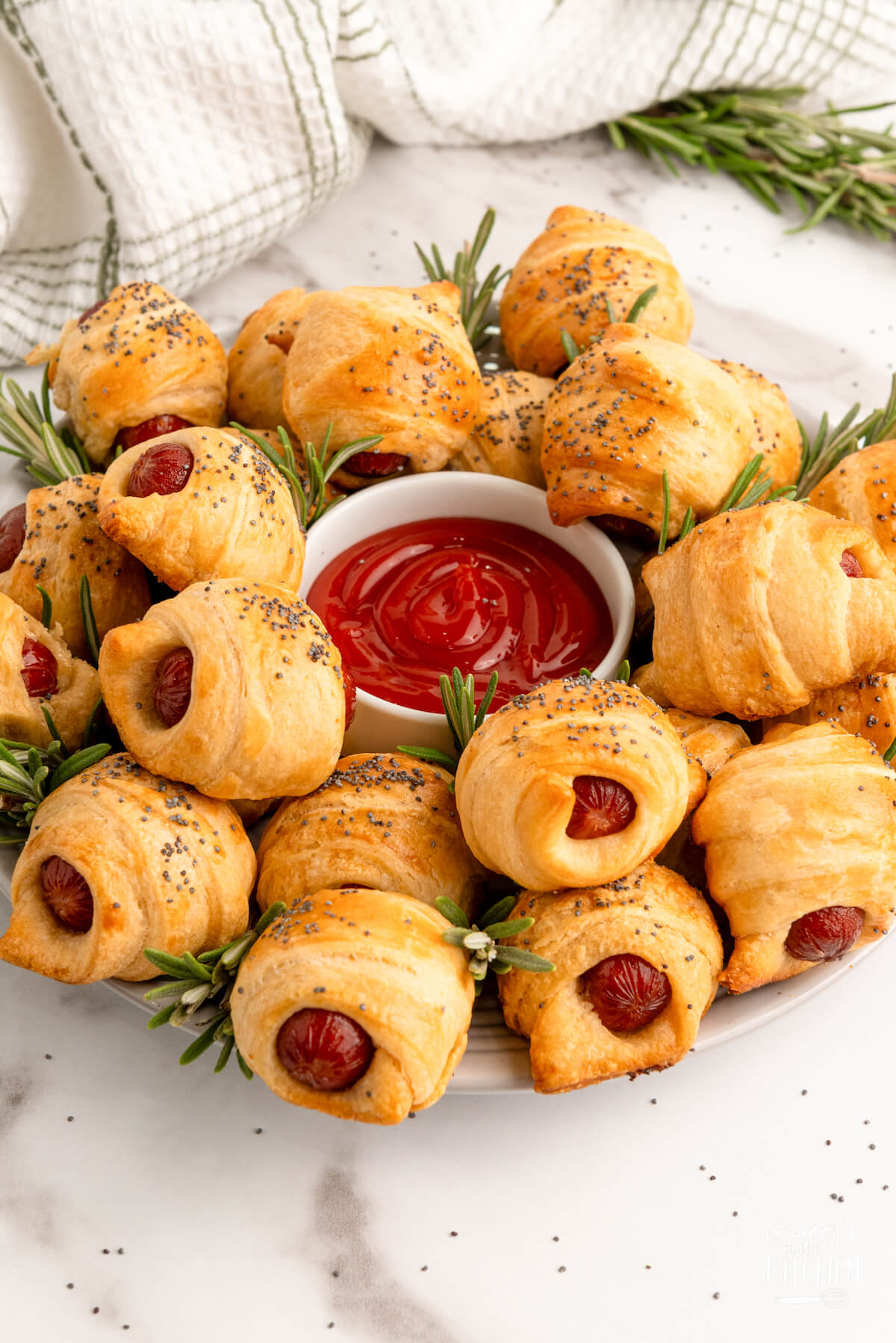mini pigs in a blanket arranged on a serving platter to look like a wreath