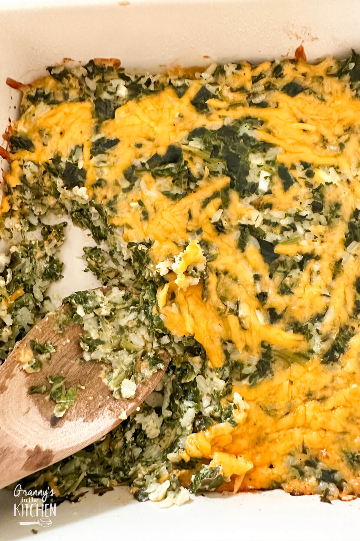 spinach rice casserole with a wooden serving spoon.