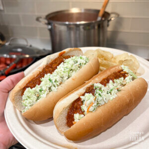 holding a plate with two West Virginia hot dogs topped with coleslaw and chili.