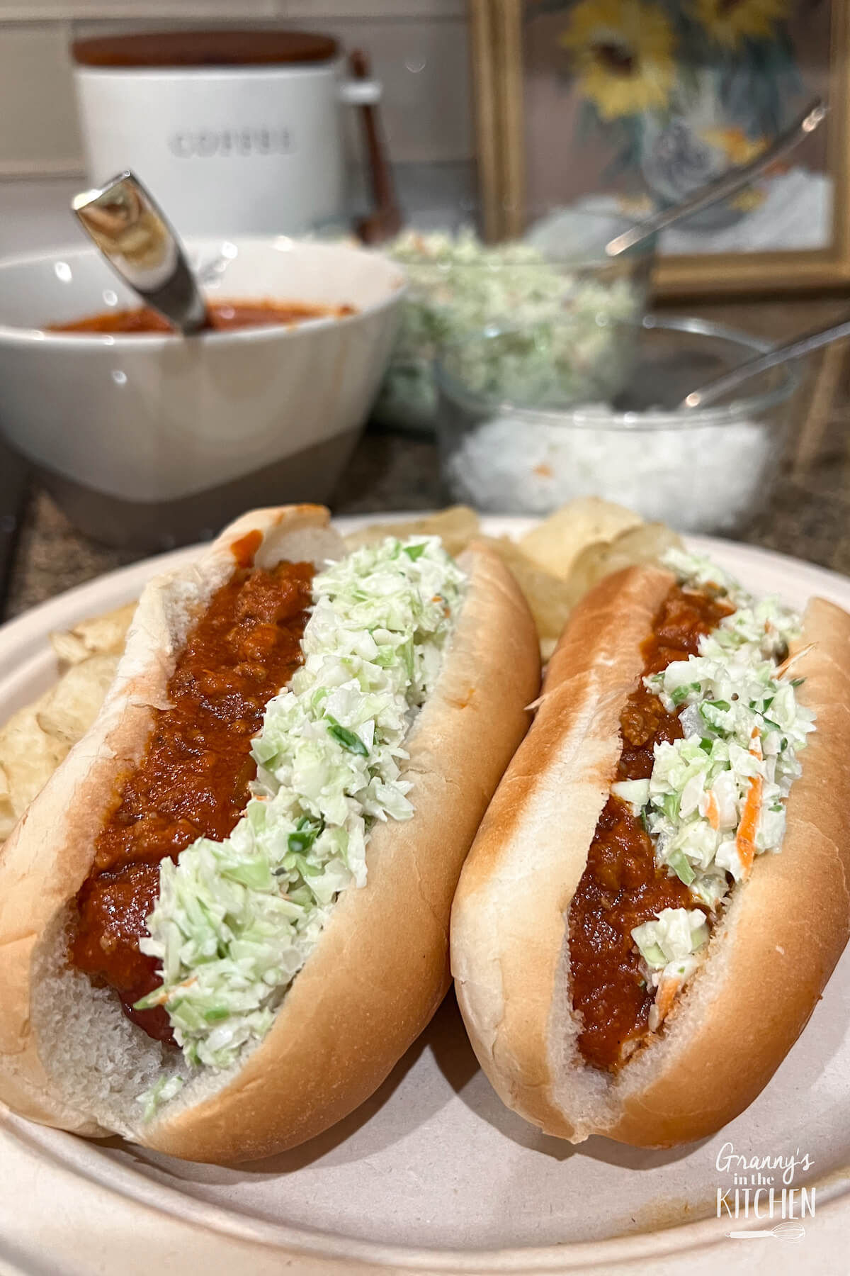 two West Virginia hot dogs on a paper plate, topped with chili and coleslaw.