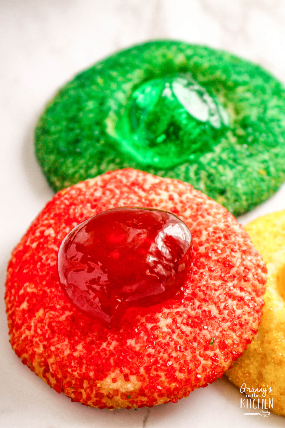close up of red and green Christmas thumbprint cookies, made with colorful sugar.