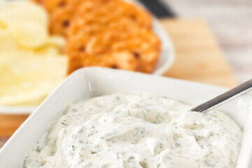 bowl of dill dip with chips and pretzels in background; text overlay "Easy Dill Dip".
