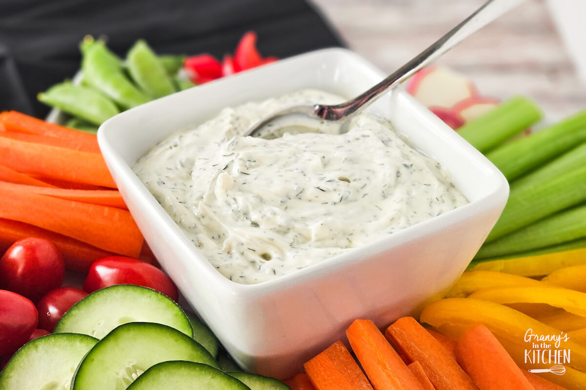 bowl of dill dip surrounded by sliced fresh veggies.