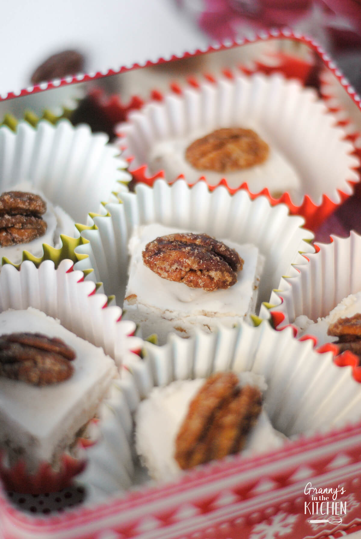 close up of an open tin filled with divinity candy with pecan halves on top.