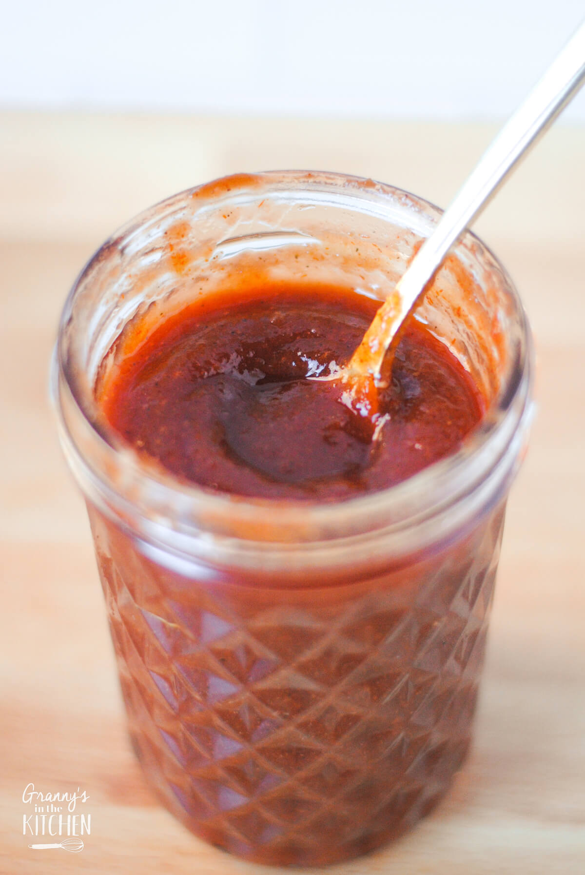 mason jar of homemade bbq sauce with a spoon inside.