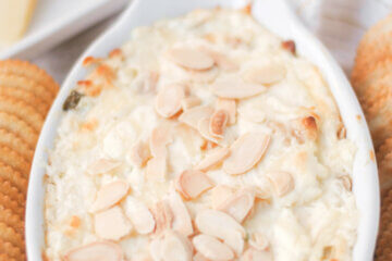 baking dish with melted Swiss cheese dip topped with sliced almonds; text overlay "Hot Swiss Dip".
