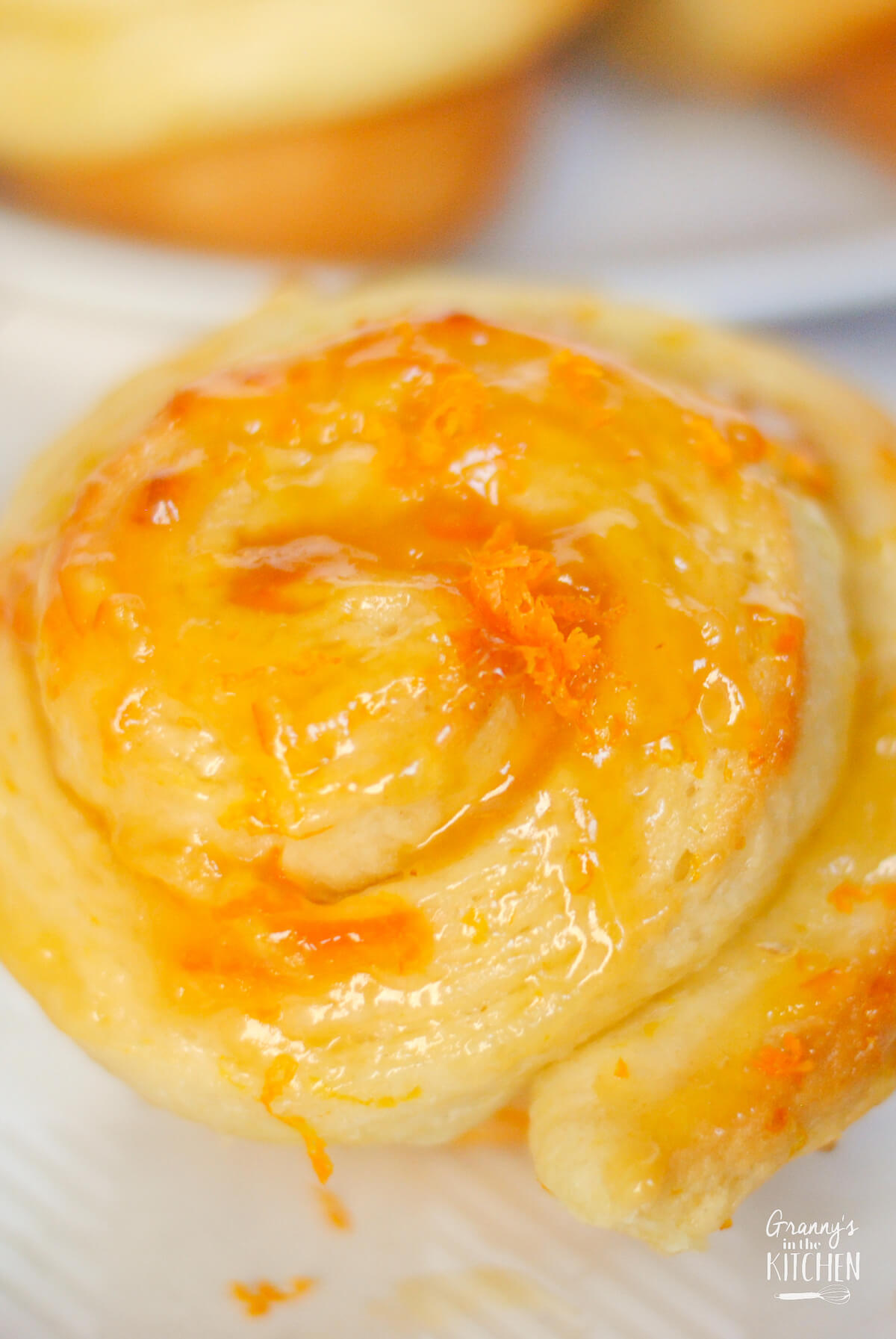 close up of a glazed orange roll.