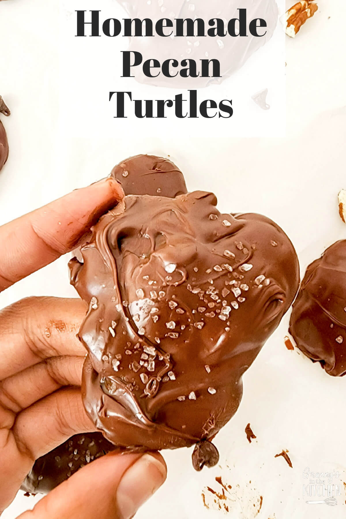 holding a pecan turtle candy close up; text overlay "Homemade Pecan Turtles".
