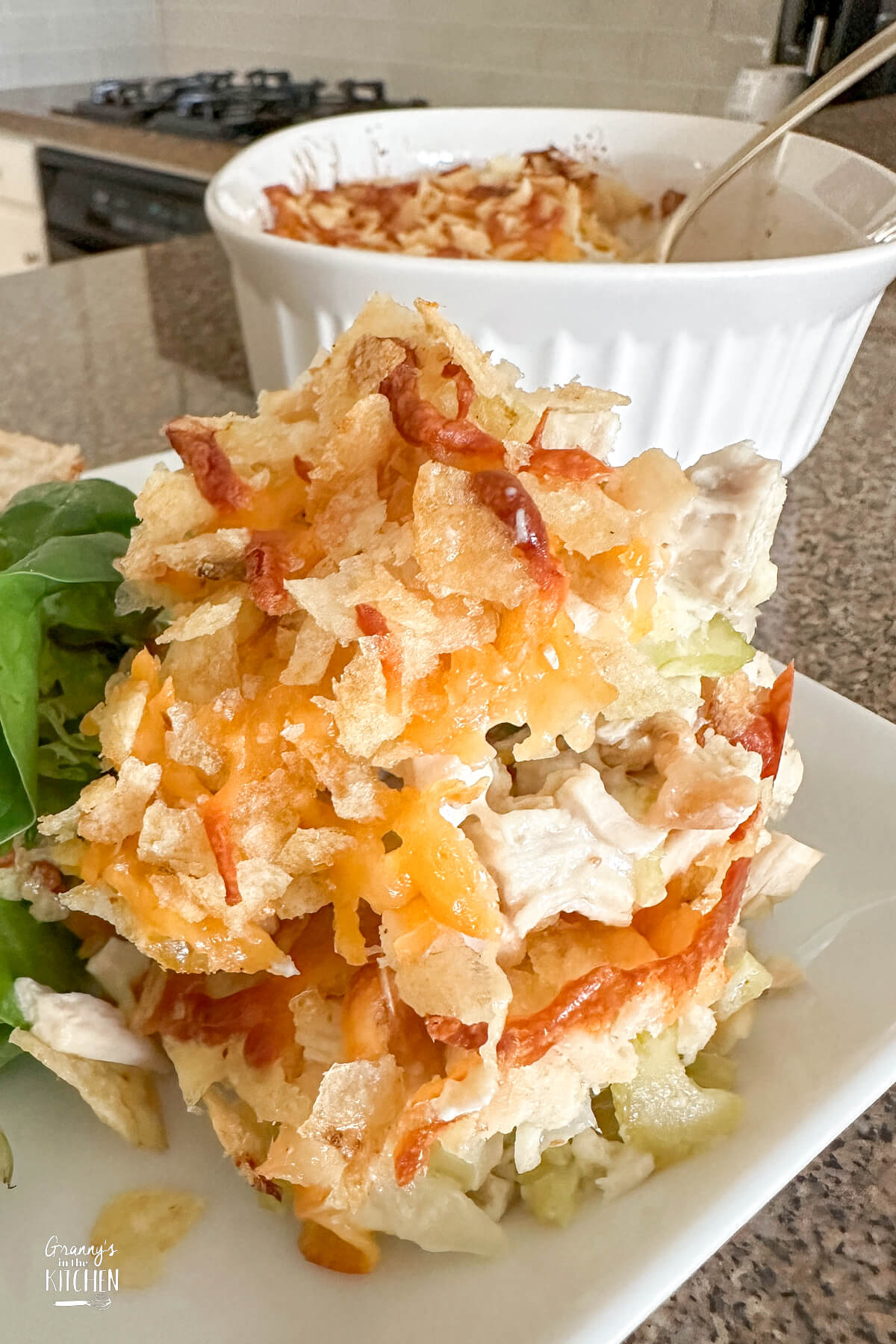 hot chicken salad on plate, with casserole dish in background.