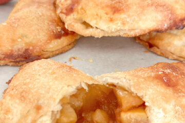 mini apple pie, cut in half to show filling, text overlay "Apple Hand Pies."