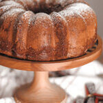 chocolate bundt cake on a cake stand, surrounded by mini Hersey bars.