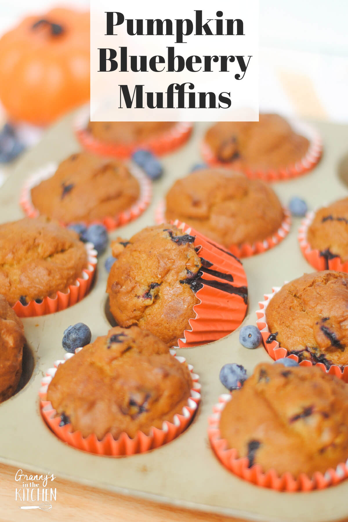 muffins in a muffin pan, with text overlay "Pumpkin Blueberry Muffins".