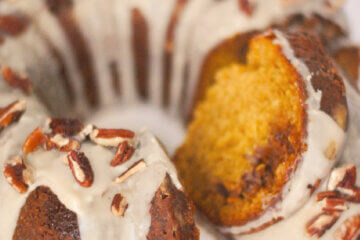bundt cake topped with glaze and pecans, text overlay "Pumpkin Praline Cake."