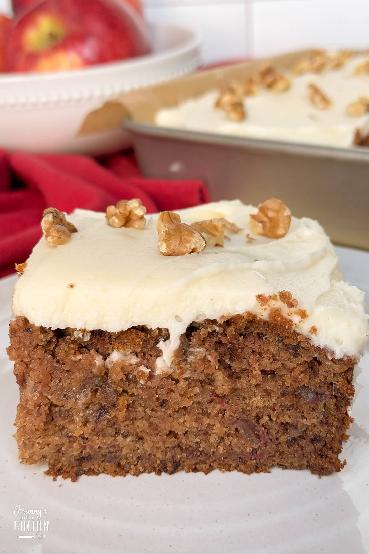 close up of a slice of brown applesauce cake topped with cream cheese frosting.